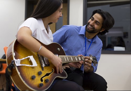 pupil and teacher playing guitar