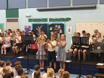 A group of pupils from Grangefield Primary performing with their trumpets to another group of students