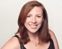 A photo of Suzzie Vango against a white background. She has shoulder length brown hair, black eyes and is wearing a black vest top with a necklace. She is smiling at the camera.